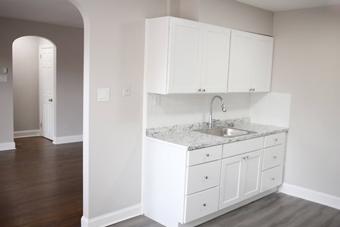 A kitchen with white cabinets and a marble countertop.