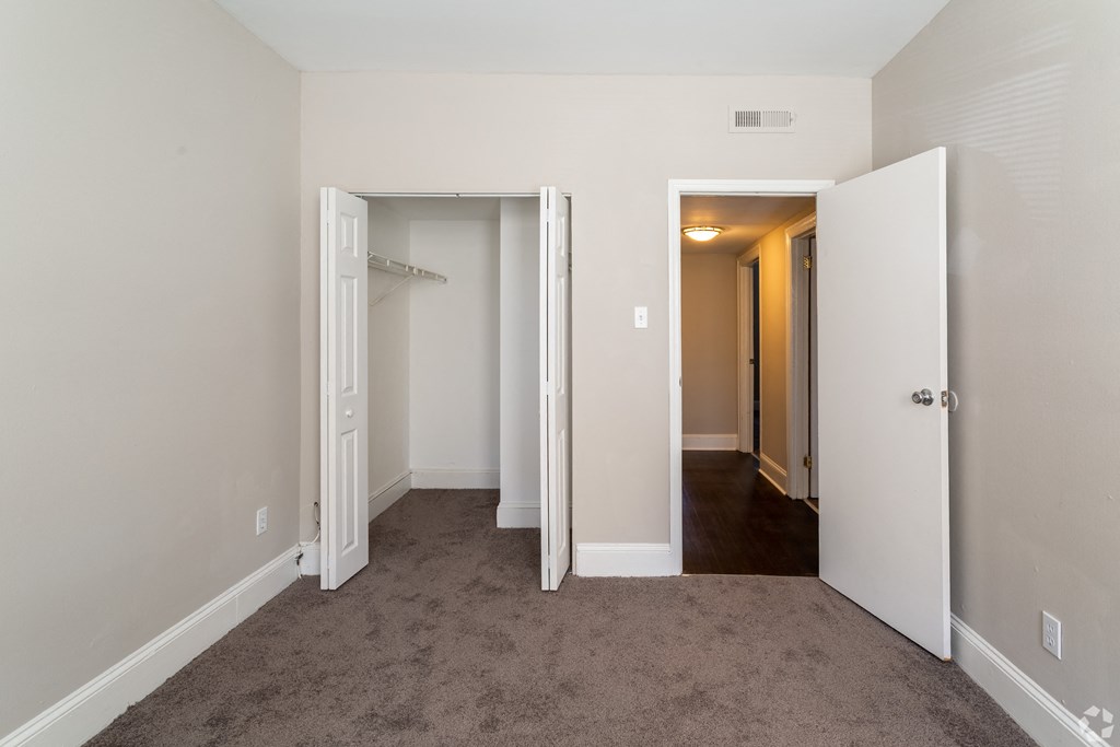 a bedroom with two closets and a carpeted floor and a hallway with doors