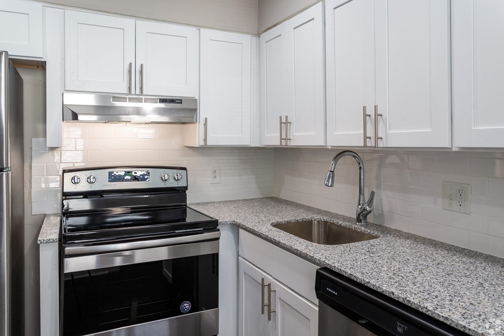 a kitchen with white cabinets and granite counter tops and a sink