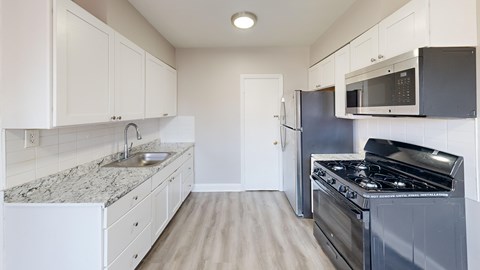 A kitchen with a stove, sink, and cabinets.