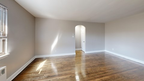 A room with wooden floors and a doorway leading to another room.