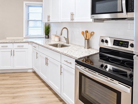 A kitchen with white cabinets and a black stove top.