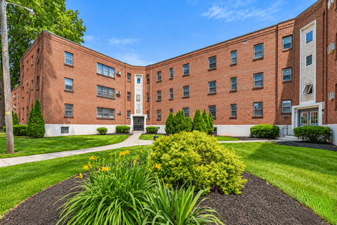 A red brick building with a garden in front.