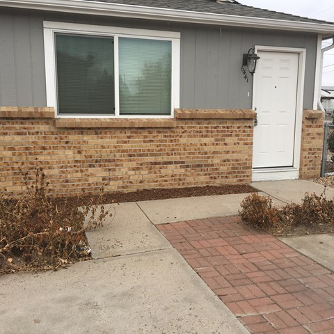 A house with a white door and a brick wall.