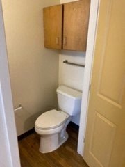 a bathroom with a white toilet and wooden floors