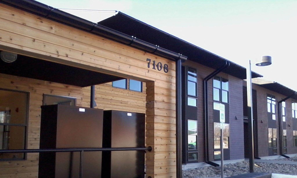 front of building shows wood panels and chocolate brown siding