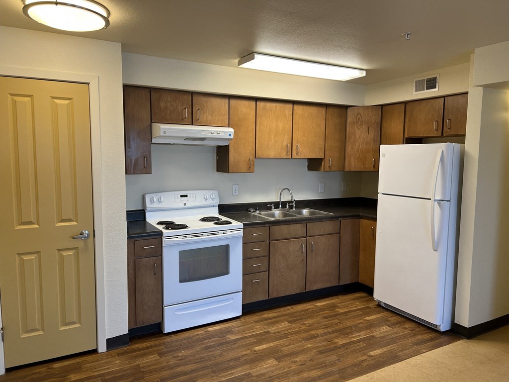 an empty kitchen with white appliances and wooden cabinets