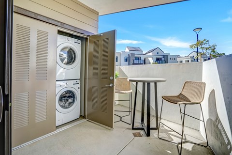 A washing machine is in a small room with a table and chairs.