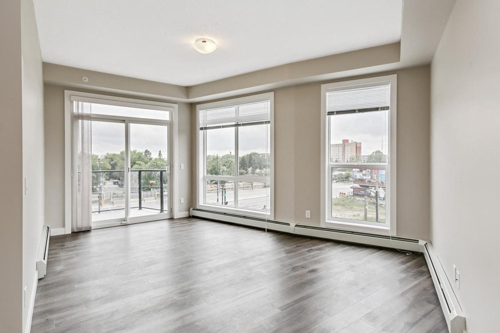 an empty living room with large windows and wood floors