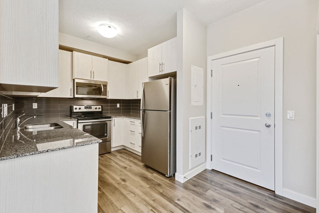 an empty kitchen with stainless steel appliances and white cabinets