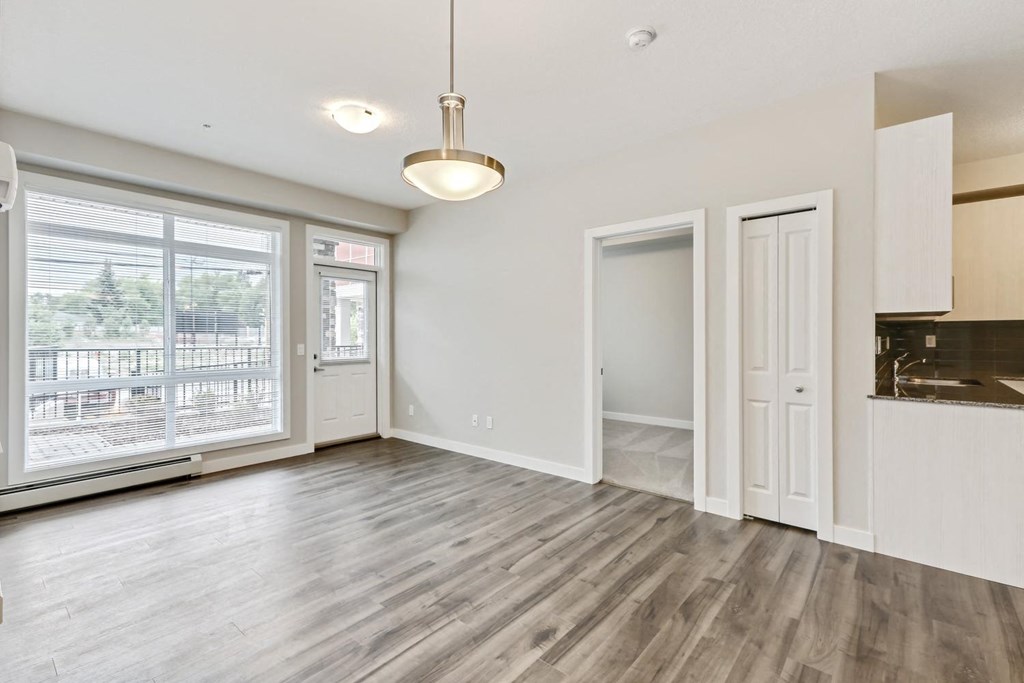an empty living room with a large window and a door to a kitchen