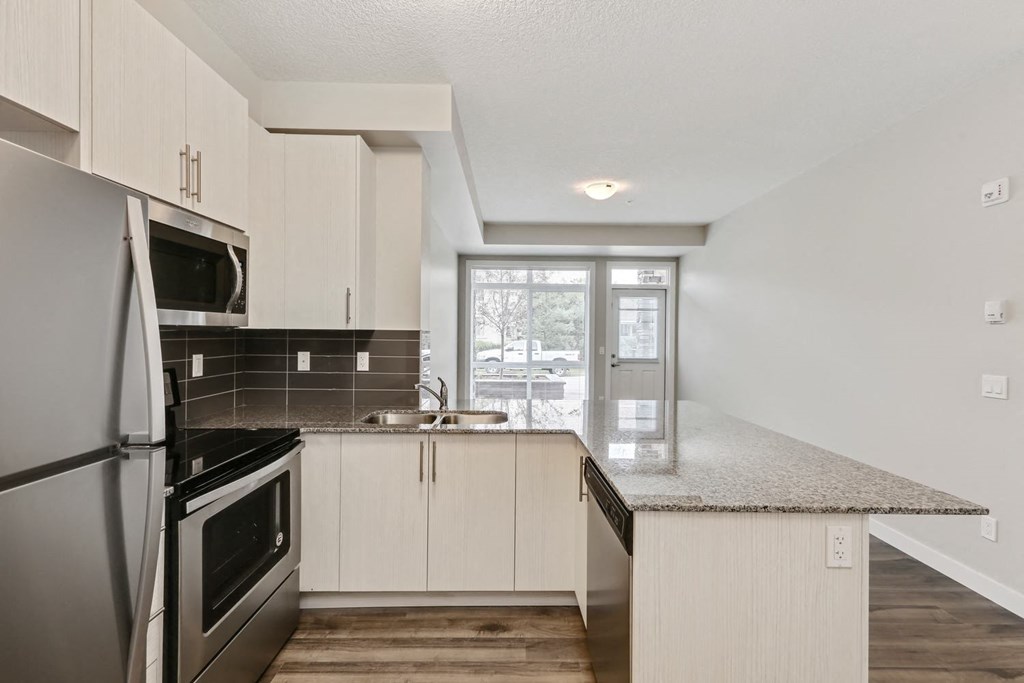 an empty kitchen with white cabinets and stainless steel appliances