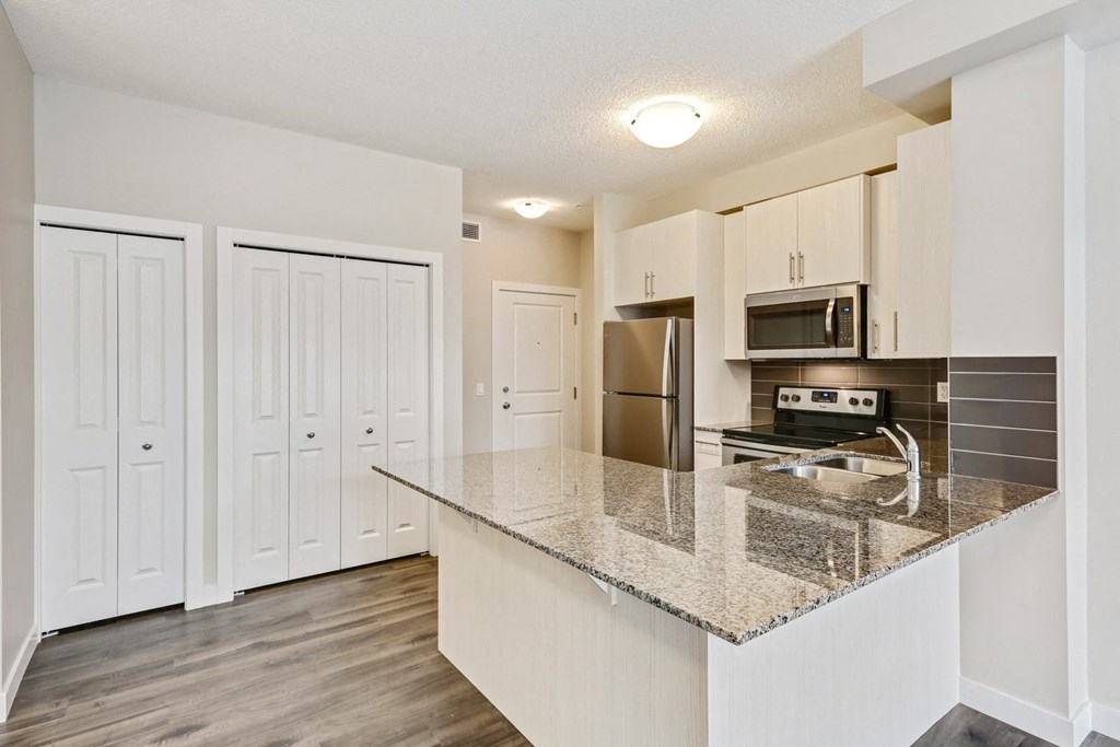 a kitchen with a granite counter top and a stainless steel refrigerator