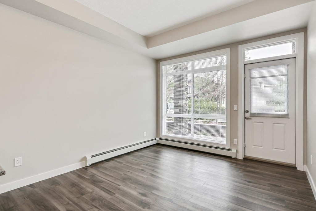 the living room of an empty home with a large window and a door