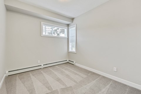 an empty bedroom with a window and a carpeted floor