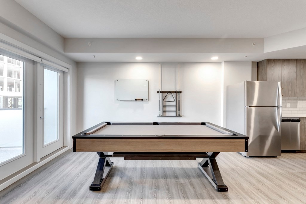 a pool table in a living room with a refrigerator and a window