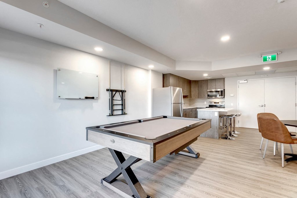 a game room with a pool table and a kitchen