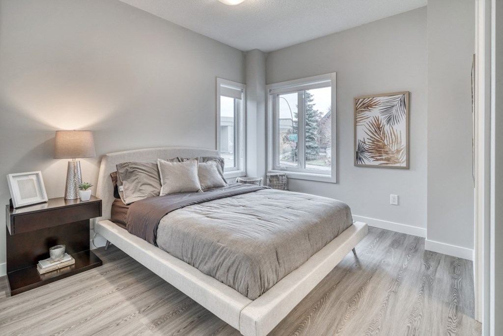 the master bedroom in a new home with a bed and two windows