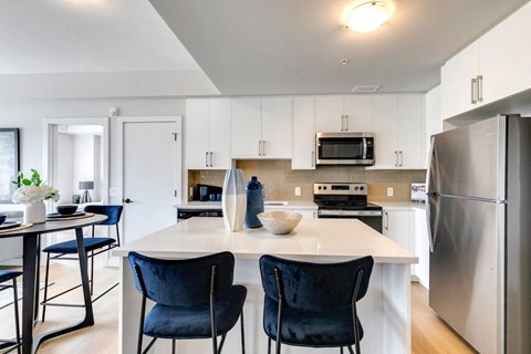 a kitchen with a large island with blue chairs