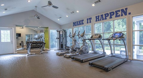 A gym with treadmills and a sign that says "make it happen".