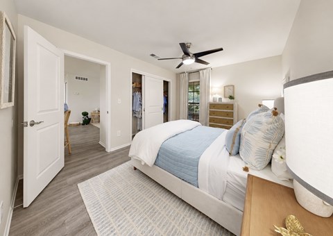 A bedroom with a bed, dresser, and a ceiling fan.