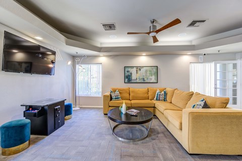 A living room with a yellow couch and a coffee table.