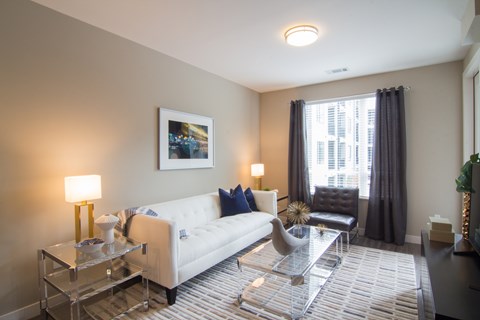 A living room with a white couch, a glass coffee table, and a framed picture on the wall.