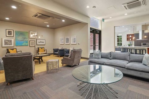 A modern living room with a glass table and grey couches.