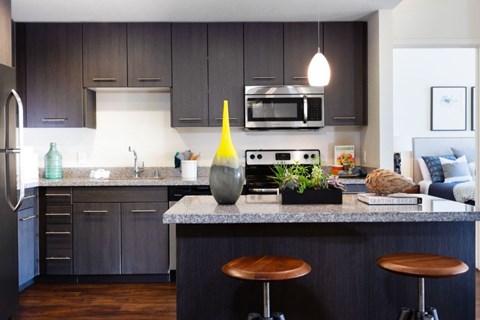 A kitchen with dark wood cabinets and a granite countertop.