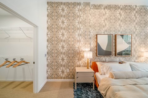 A bedroom with a bed, nightstand, and two framed pictures on the wall.