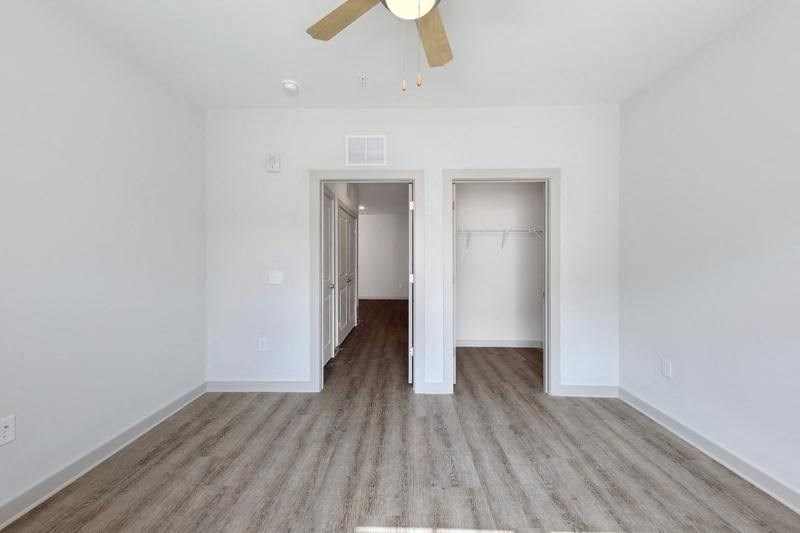 a bedroom with white walls and a ceiling fan