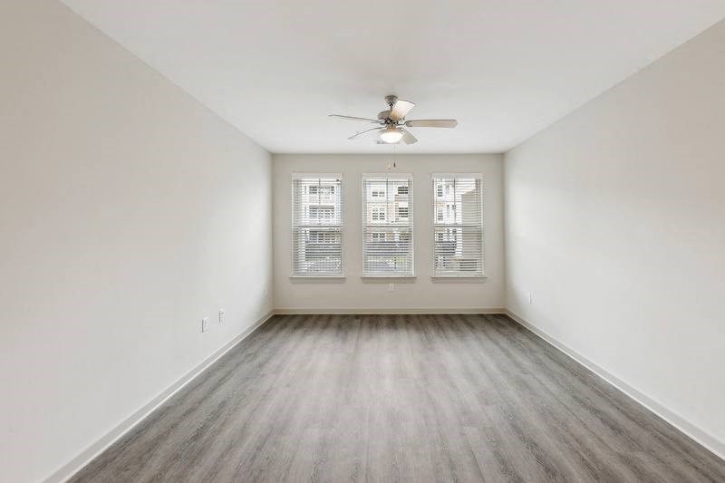 an empty room with a ceiling fan and three windows