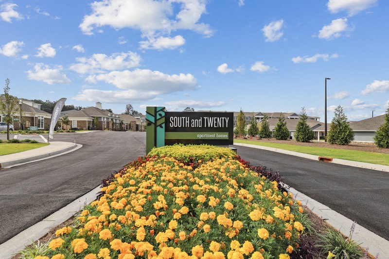 a community sign with yellow flowers in front of it