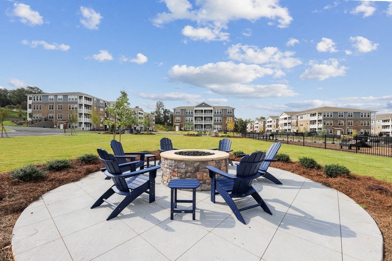 an outdoor patio with a firepit and blue adirondack chairs