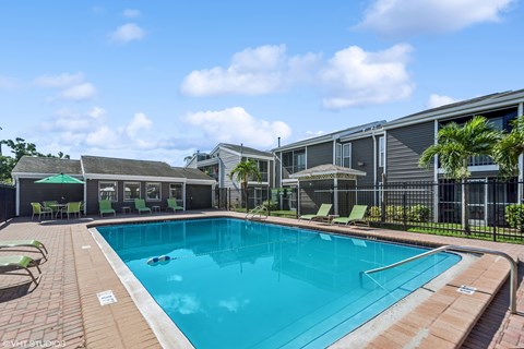 A swimming pool surrounded by a fence and chairs.