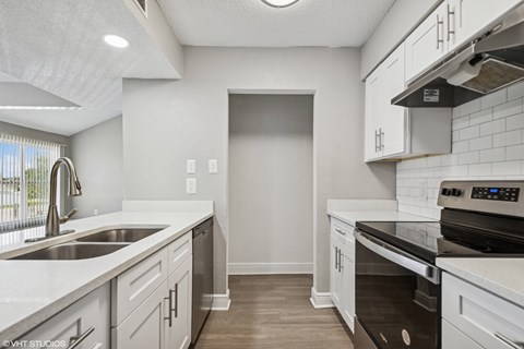 A kitchen with white cabinets and a black stove top oven.