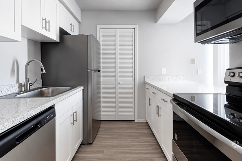 A kitchen with white cabinets and black appliances.