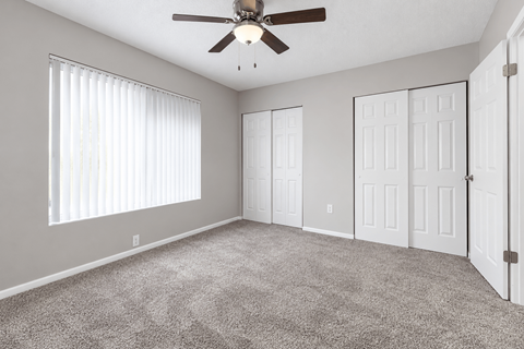 A room with a ceiling fan and carpeted floor.