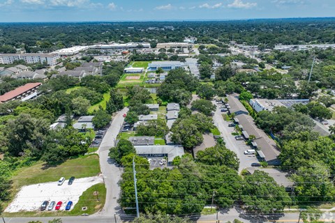 A bird's eye view of a green campus with buildings and cars.