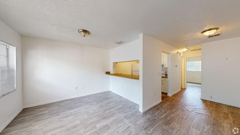 A spacious room with wooden flooring and white walls.