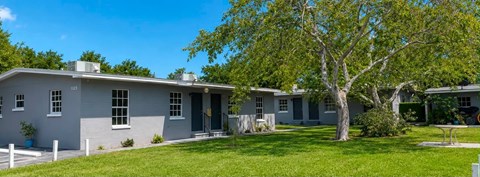 A grey house with a tree in front.