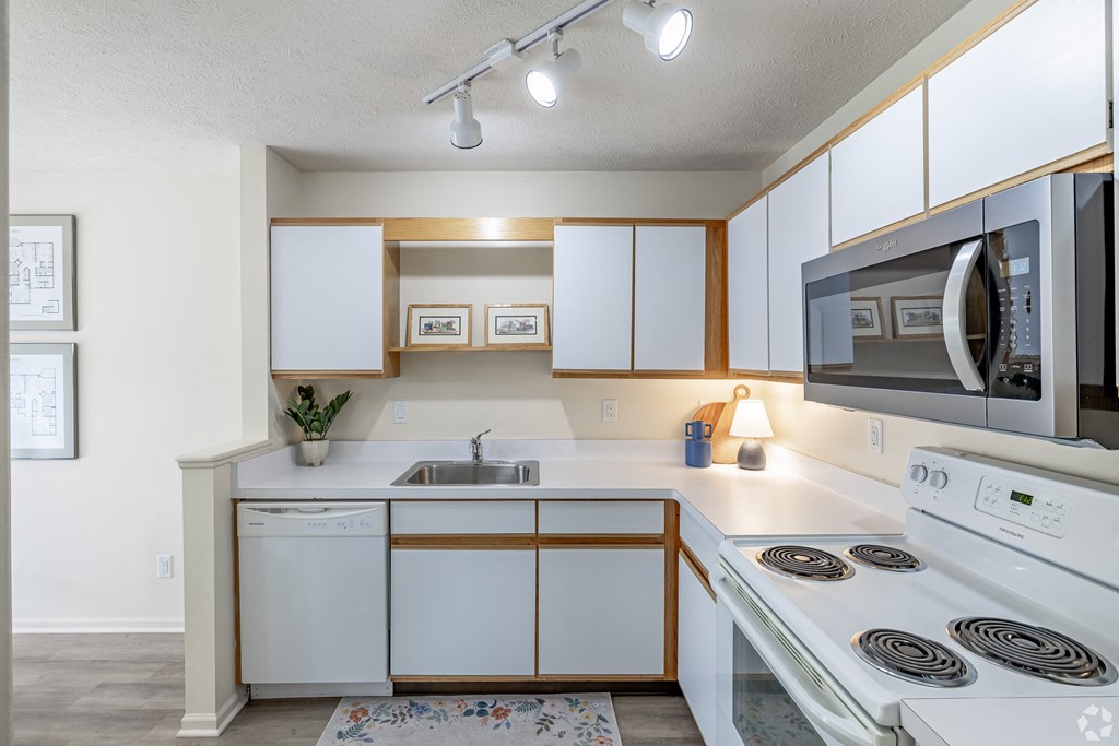 A white kitchen with wooden accents and a white stove top oven.