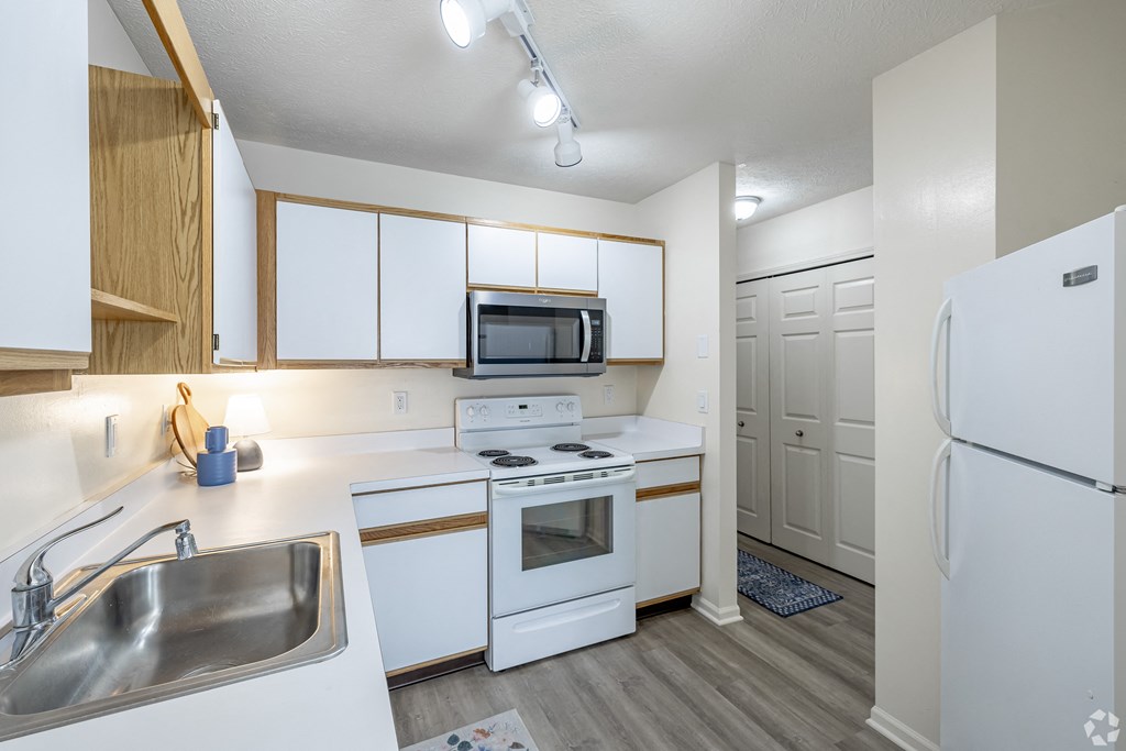 A kitchen with white appliances and wooden cabinets.