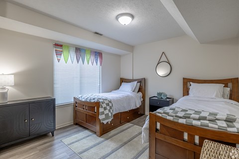 A bedroom with two beds and a nightstand.
