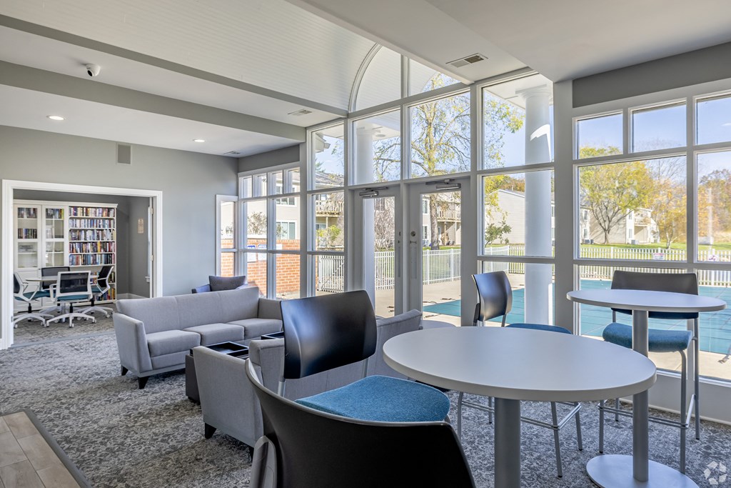A room with a table and chairs with a view of a pool outside.