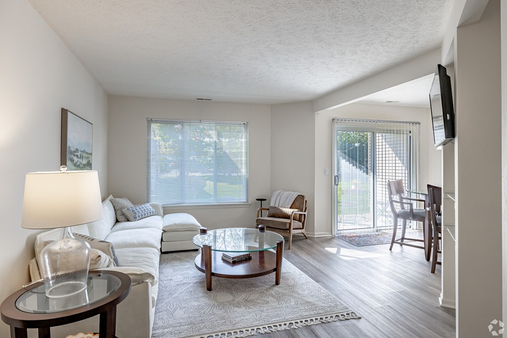 A living room with a white couch and a glass coffee table.