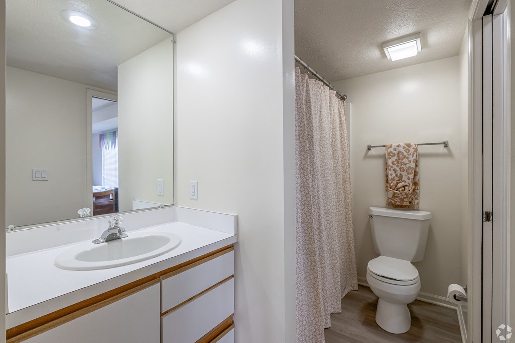 A white bathroom with a sink, toilet, and shower.