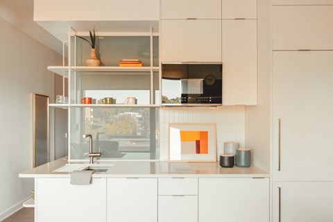 A modern kitchen with white cabinets and a glass countertop.