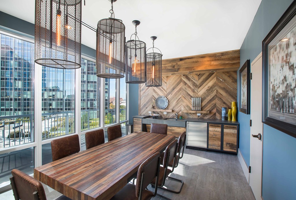 a dining room with a long wooden table and chairs and large windows