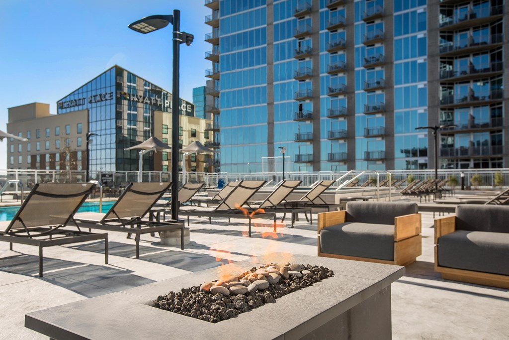 a group of lounge chairs around a fire pit on a patio next to a pool